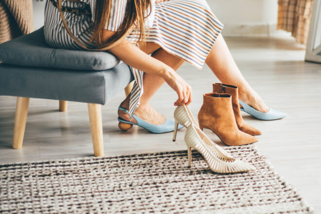 Fashionable young woman in striped dress trying new shoes while Fashionable young woman in striped dress trying new shoes while